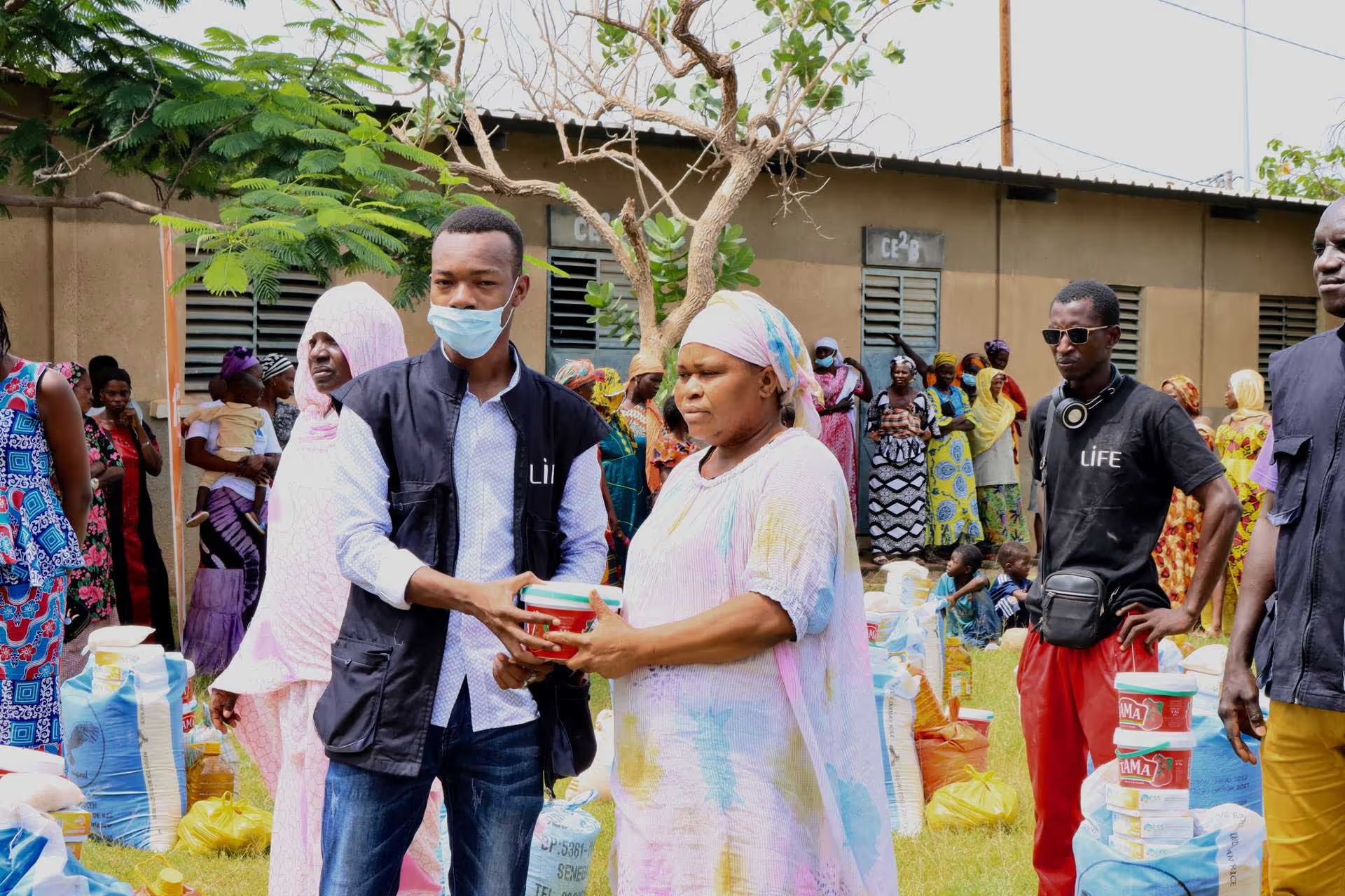 Un membre de l'équipe LIFE remet un colis alimentaire à une habitante lors d'une distribution au Sénégal.