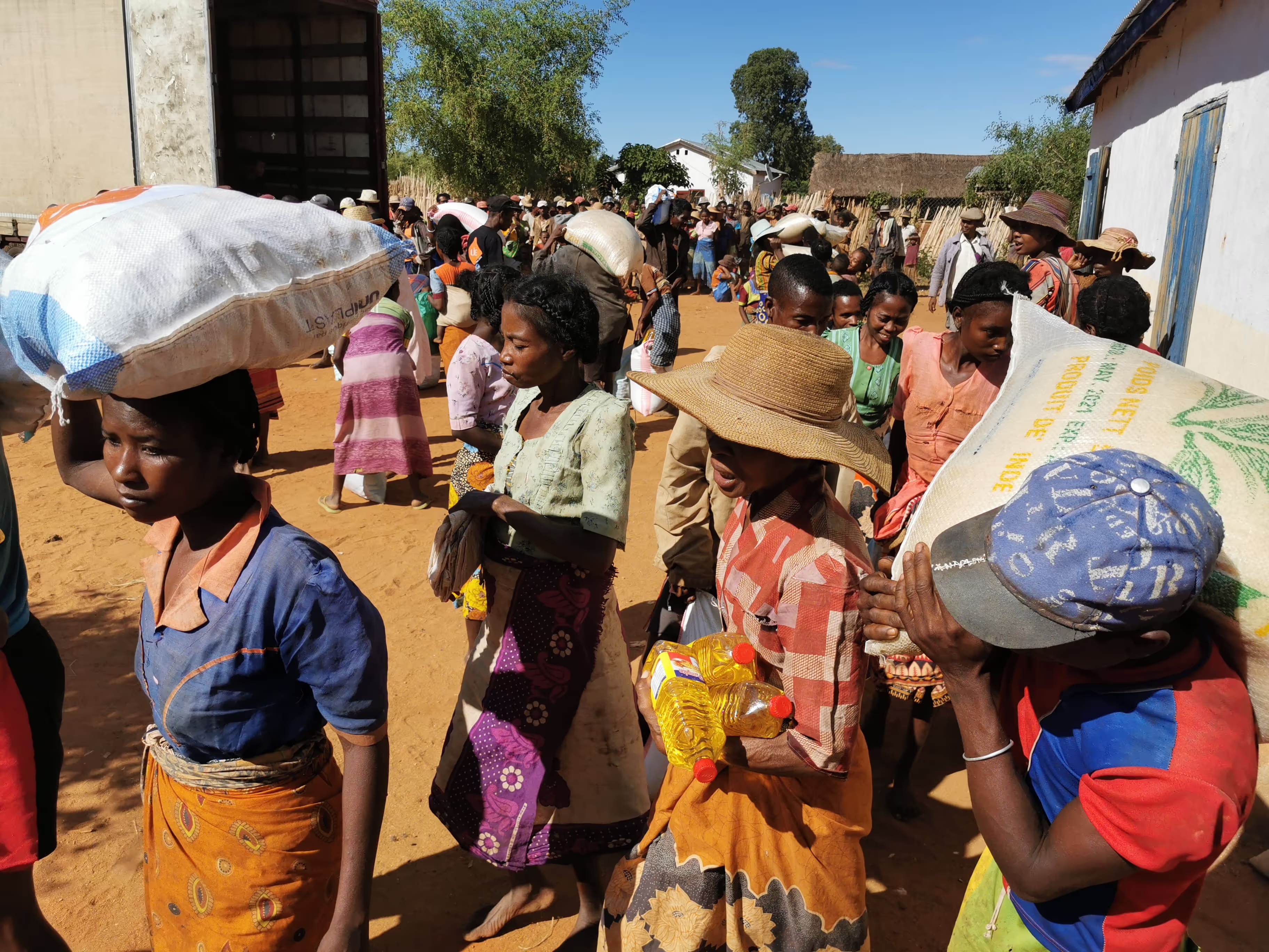 Des habitants portent les sacs de riz d'une distribution alimentaire LIFE à Madagascar.