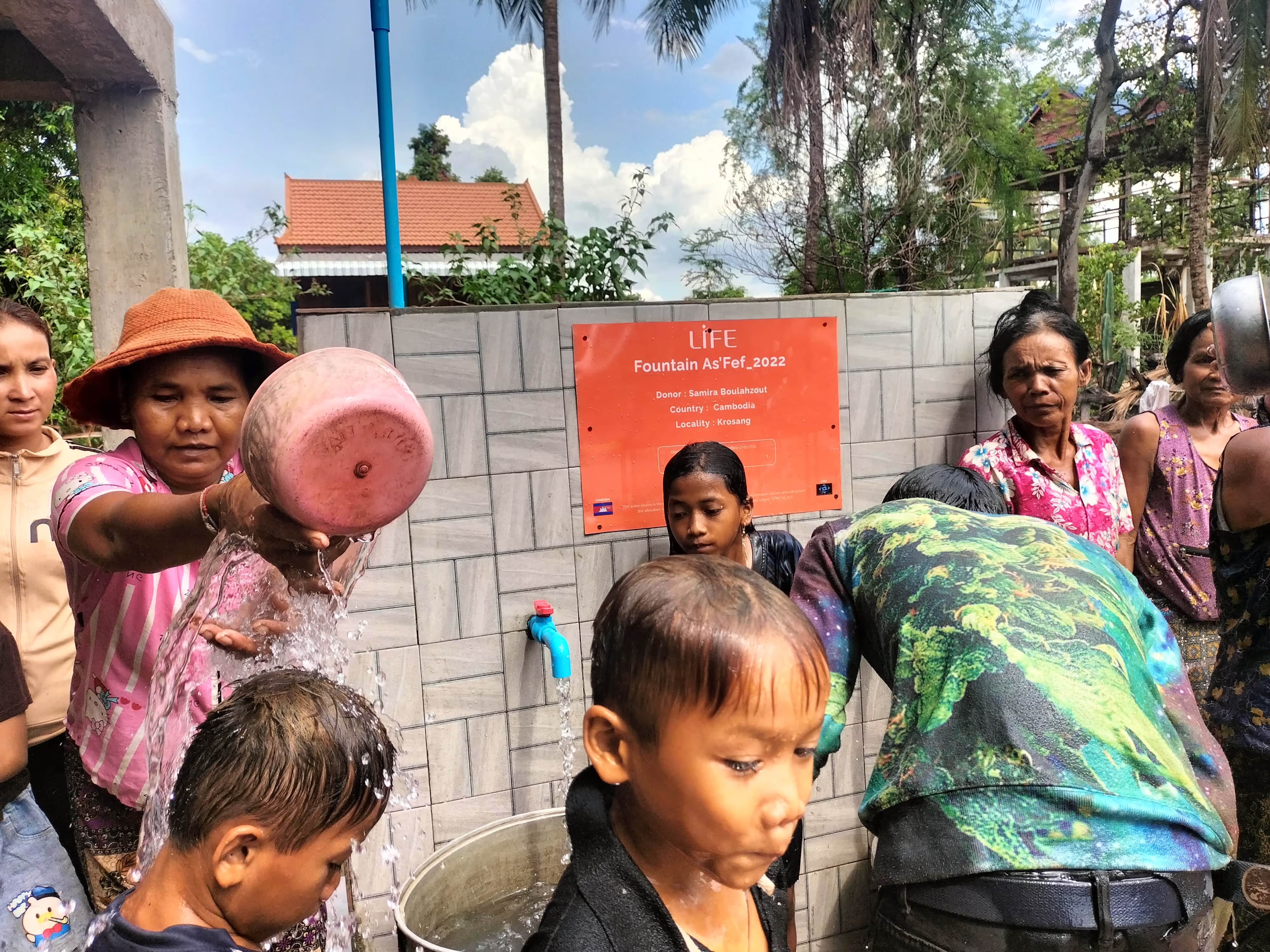 Des femmes et des enfants se rincent à la fontaine d'eau potable construite par LIFE à Krosang, au Cambodge.